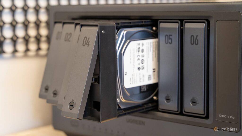 multiple drive trays pulled out from the ugreen idx6011 pro nas with a hard drive visible inside the.jpeg