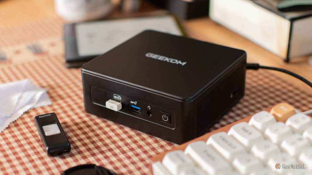 the geekom it15 mini pc on a desk with a keyboard and ereader.jpg